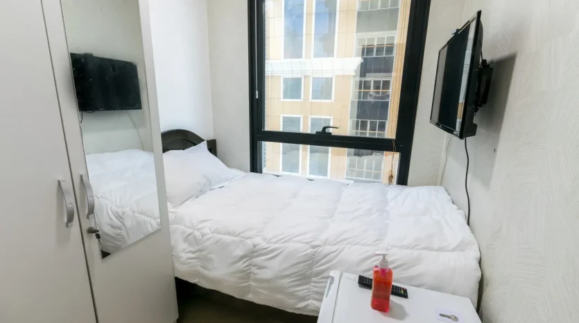 this picture shows a bed and screen inside a room in marina customized for rent at a cheap price.