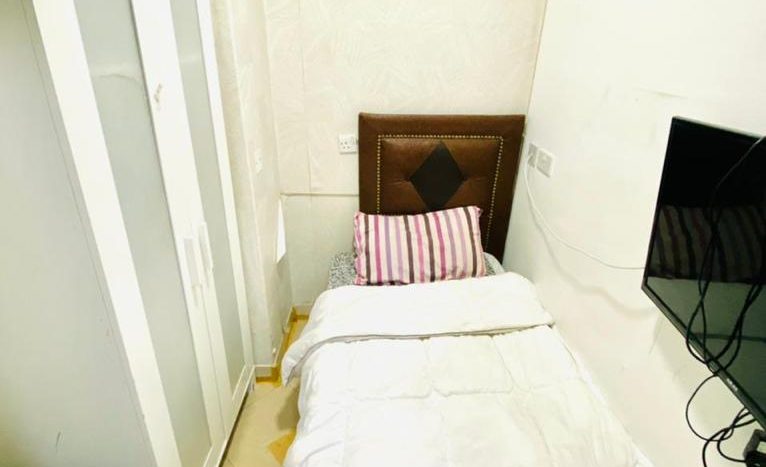 this picture shows s bed and screen in a single room in Dubai for rent available with Newbai.