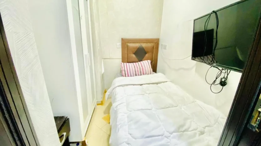 this image shows a bed and screen in a single room for rent in Dubai Marina at an exclusive price.