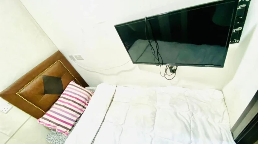 this picture includes a bed and screen inside a single room for rent in Marina Dubai.