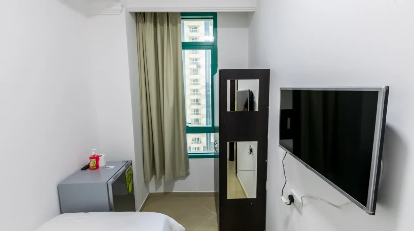 This picture shows a bed and screen inside a solo room in marina of Dubai available for rent