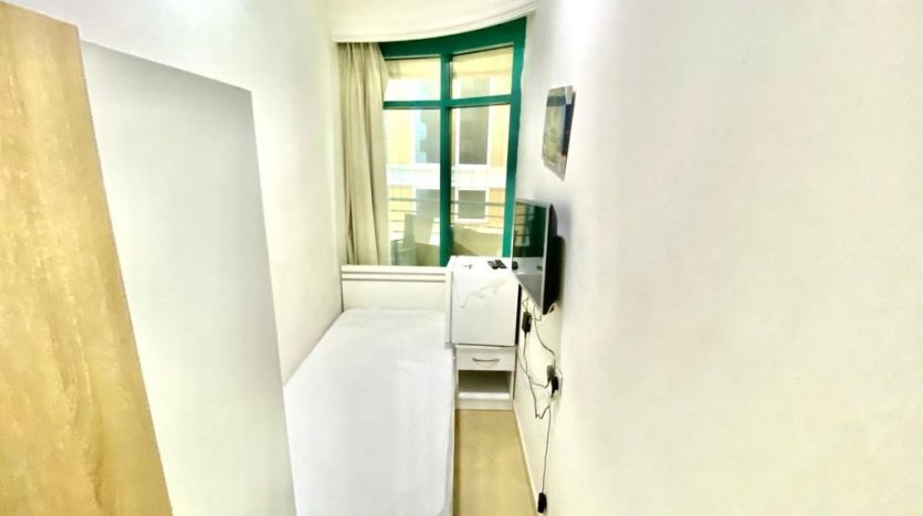 This picture shows a bed & screen TV inside a single room customized for rent in marina.