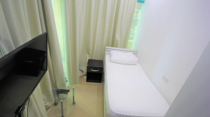 This picture shows a bed and screen inside a private room for rent in Marina Dubai at a cheap price.
