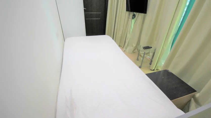 This picture shows a bed and screen inside a private room available for rent in Dubai Marina.