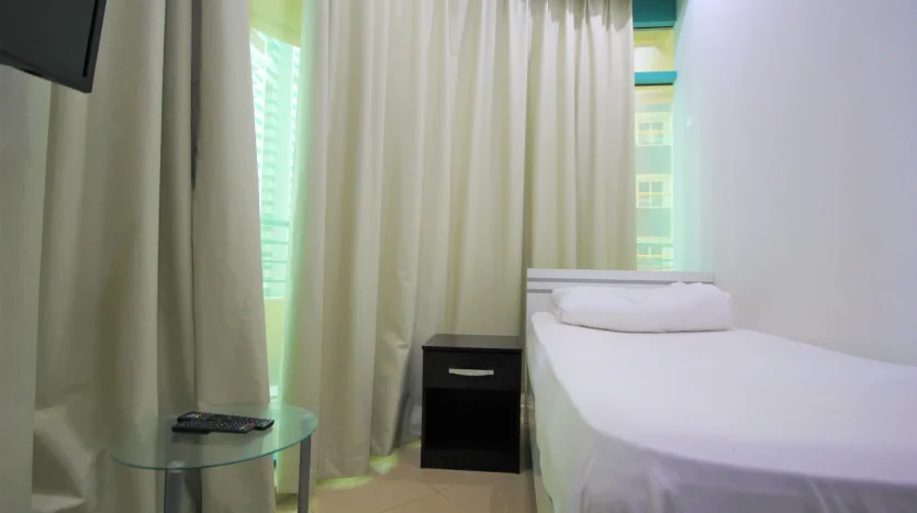 this photo includes a bed and screen in a single room available for rent in Dubai Marina.