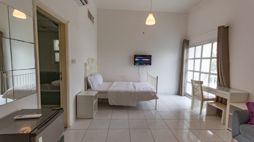 This picture includes a bed and TV screen in a room for rent in Umm Suqeim
