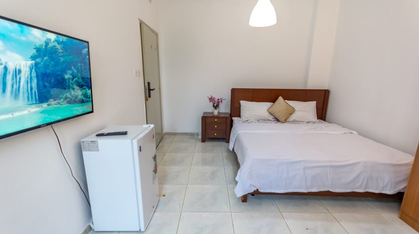 This picture shows a bed and TV screen in a Small room in umm suqeim for rent.